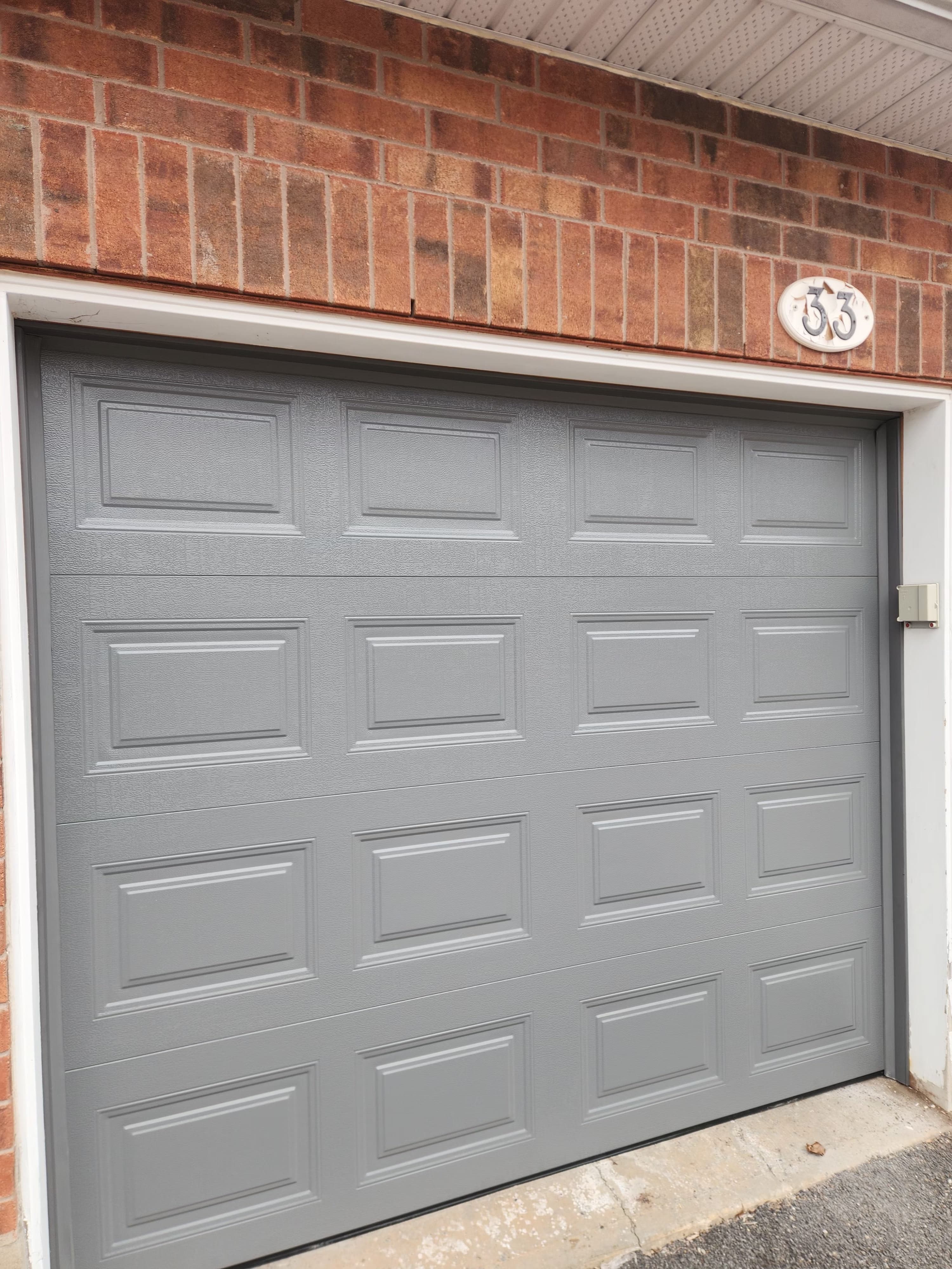 New garage door installed in Ottawa — raised-panel steel door on residential home