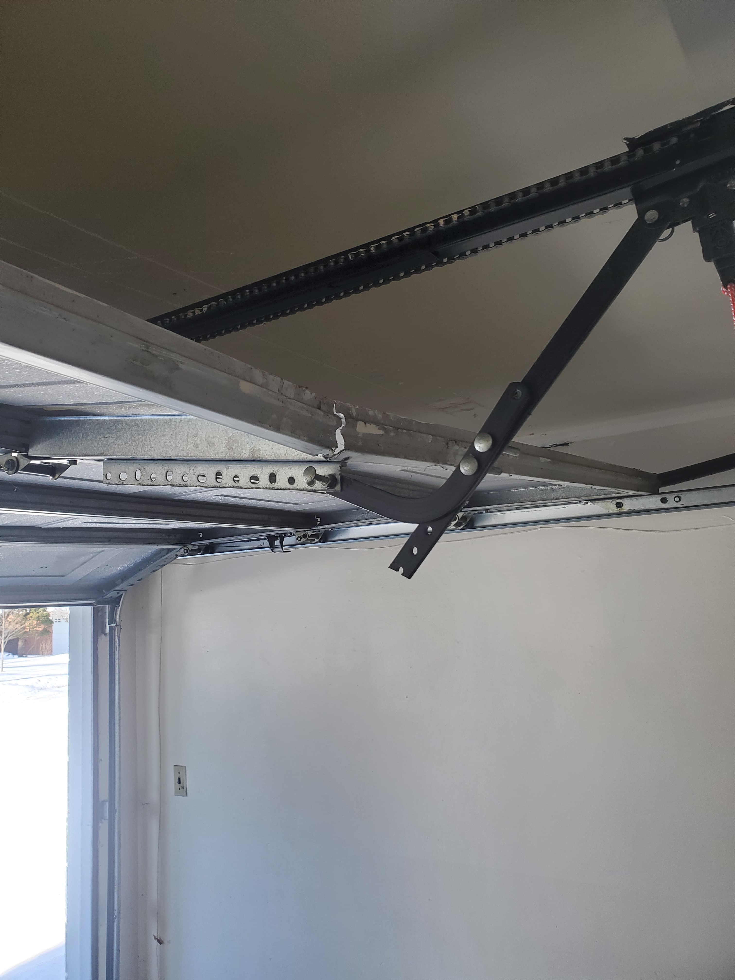 Broken garage door panel with cracked frame and disconnected opener arm — panel repair Ottawa