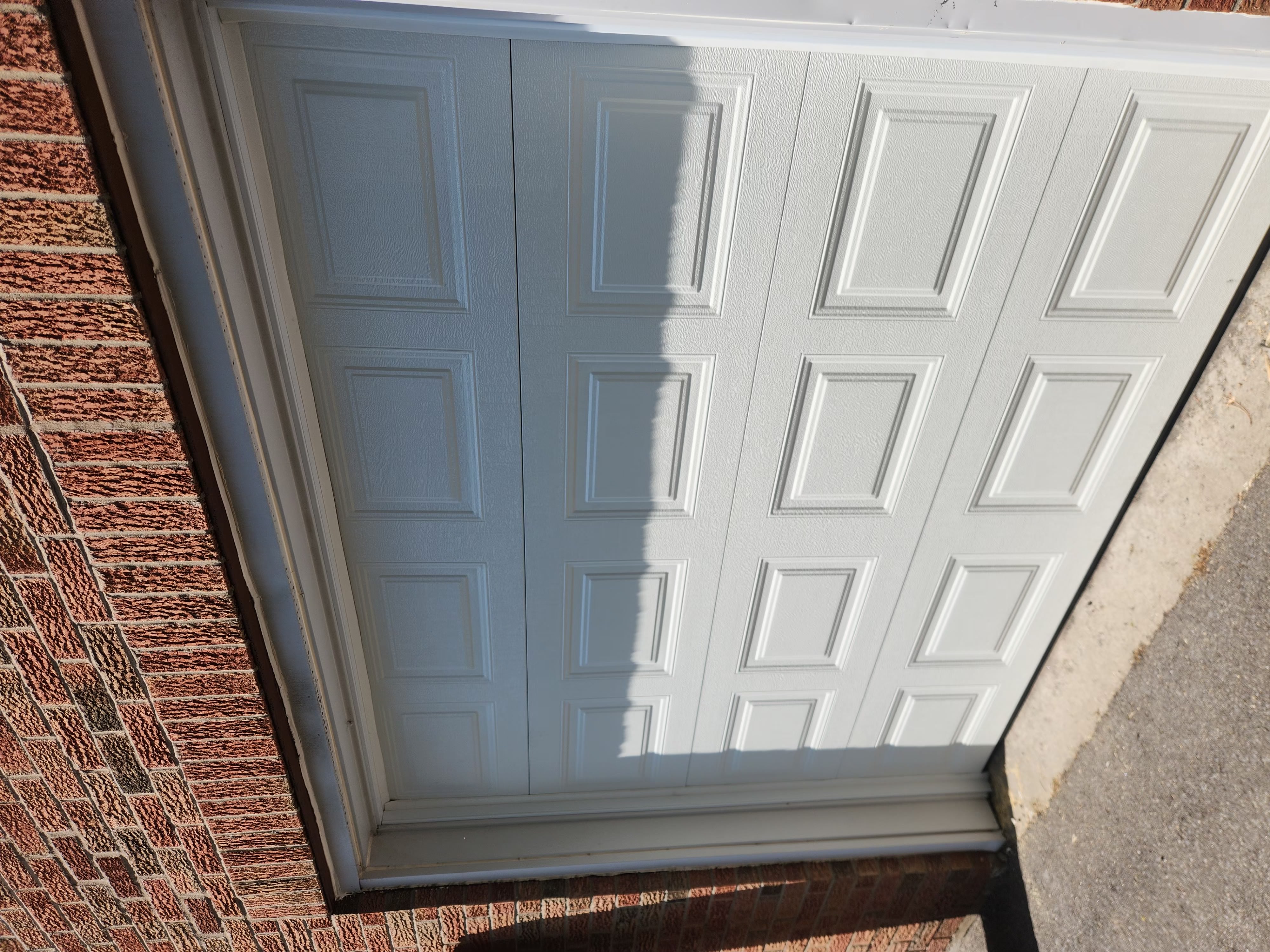 New white raised-panel garage door installation on brick home in Ottawa — new door install