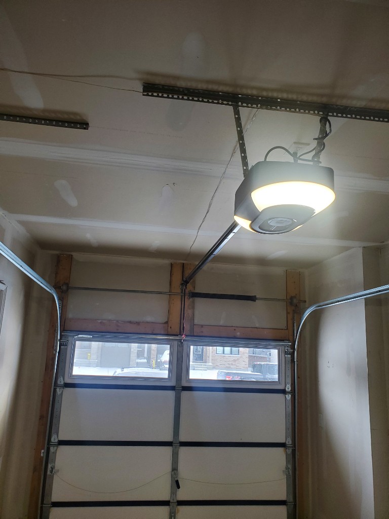 Garage door opener motor installed on ceiling with rail and trolley — opener repair in Ottawa